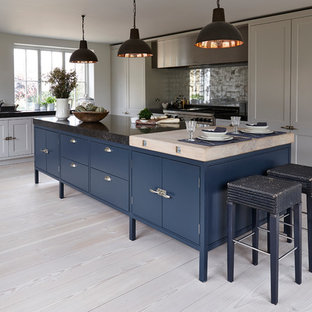 Esempio di una cucina tradizionale con ante grigie, paraspruzzi a effetto metallico, elettrodomestici in acciaio inossidabile e parquet chiaro