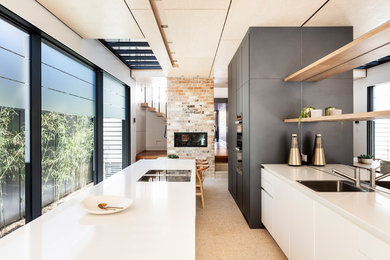 Zweizeilige Moderne Wohnküche mit Einbauwaschbecken, flächenbündigen Schrankfronten, grauen Schränken, Rückwand-Fenster, Betonboden, Kücheninsel, beigem Boden und weißer Arbeitsplatte in Sydney