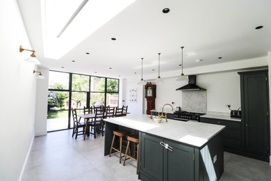 This is an example of a contemporary single-wall kitchen in London with a belfast sink, recessed-panel cabinets, grey cabinets, marble worktops, grey splashback, marble splashback, stainless steel appliances, an island, grey floors and grey worktops.
