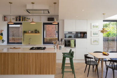ロンドンにあるコンテンポラリースタイルのおしゃれなキッチン (アンダーカウンターシンク、フラットパネル扉のキャビネット、白いキャビネット、シルバーの調理設備、無垢フローリング、茶色い床) の写真
