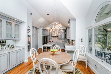 Eat-in kitchen - mid-sized transitional u-shaped medium tone wood floor eat-in kitchen idea in Atlanta with shaker cabinets, gray cabinets, granite countertops, gray backsplash, mosaic tile backsplash, stainless steel appliances, an island and a double-bowl sink