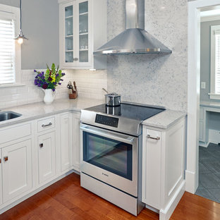 Small arts and crafts u-shaped eat-in kitchen in Other with an undermount sink, shaker cabinets, white cabinets, quartz benchtops, white splashback, porcelain splashback, stainless steel appliances, medium hardwood floors and with island.