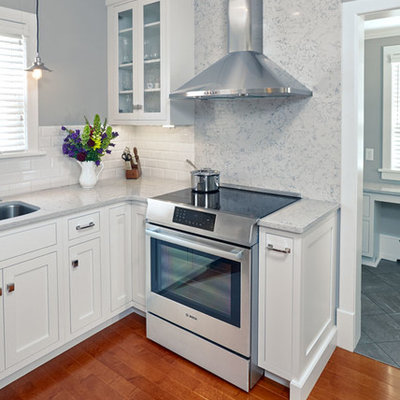 Example of a small arts and crafts u-shaped medium tone wood floor eat-in kitchen design in Other with an undermount sink, shaker cabinets, white cabinets, quartz countertops, white backsplash, porcelain backsplash, stainless steel appliances and an island