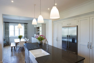 Idéer för ett modernt kök, med en dubbel diskho, luckor med infälld panel, granitbänkskiva, rostfria vitvaror, ljust trägolv och en köksö