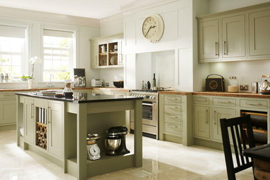 Idéer för ett stort klassiskt l-kök, med skåp i shakerstil, gröna skåp, träbänkskiva, rostfria vitvaror, en köksö och travertin golv