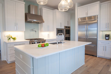 Example of a large transitional medium tone wood floor open concept kitchen design in Miami with an undermount sink, shaker cabinets, white cabinets, marble countertops, blue backsplash, glass tile backsplash, stainless steel appliances and an island