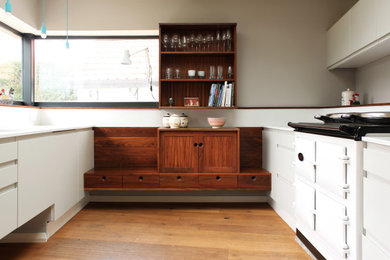 This is an example of a medium sized classic u-shaped enclosed kitchen in Cheshire with a built-in sink, recessed-panel cabinets, dark wood cabinets, quartz worktops, white splashback, engineered quartz splashback, white appliances, medium hardwood flooring, no island, brown floors and white worktops.