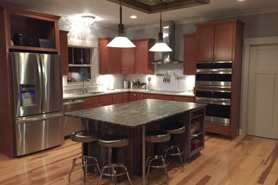 Example of a mid-sized eclectic l-shaped light wood floor eat-in kitchen design in Indianapolis with an undermount sink, shaker cabinets, medium tone wood cabinets, granite countertops, stainless steel appliances and an island