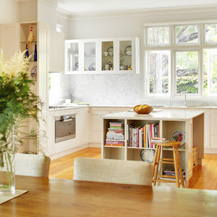 This is an example of a transitional u-shaped eat-in kitchen in Perth with an undermount sink, shaker cabinets, white cabinets, marble benchtops, grey splashback, marble splashback, white appliances, medium hardwood floors, with island and grey benchtop.