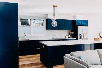 シドニーにある高級な広いトラディショナルスタイルのおしゃれなアイランドキッチン (アンダーカウンターシンク、シェーカースタイル扉のキャビネット、青いキャビネット、大理石のキッチンパネル、淡色無垢フローリング) の写真