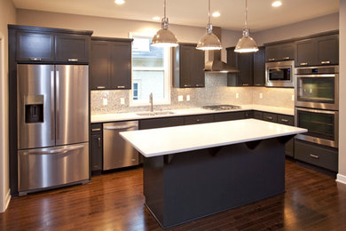 Example of a mid-sized trendy l-shaped medium tone wood floor eat-in kitchen design in Minneapolis with an undermount sink, shaker cabinets, gray cabinets, quartz countertops, metallic backsplash, mosaic tile backsplash, stainless steel appliances and an island