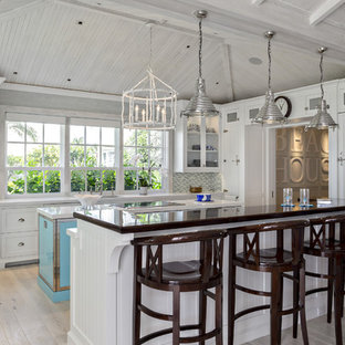 Coastal kitchen designs - Inspiration for a coastal l-shaped light wood floor and gray floor kitchen remodel in Miami with recessed-panel cabinets, white cabinets, multicolored backsplash, mosaic tile backsplash, an island and white countertops