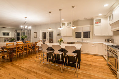 Eat-in kitchen - large transitional l-shaped medium tone wood floor eat-in kitchen idea in Cedar Rapids with an undermount sink, recessed-panel cabinets, white cabinets, granite countertops, white backsplash, subway tile backsplash, stainless steel appliances and an island