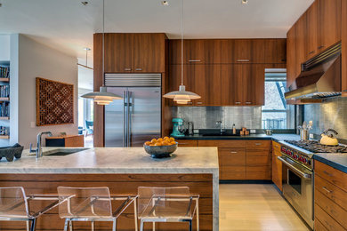 Foto di una cucina a L design con lavello sottopiano, ante lisce, ante in legno scuro, paraspruzzi a effetto metallico e elettrodomestici in acciaio inossidabile