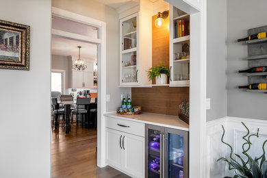 Eat-in kitchen - u-shaped brown floor eat-in kitchen idea in Other with shaker cabinets, white cabinets, quartz countertops, white backsplash, subway tile backsplash, stainless steel appliances, an island, white countertops and a farmhouse sink