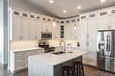 Kitchen pantry - mid-sized contemporary l-shaped medium tone wood floor and gray floor kitchen pantry idea in Denver with an undermount sink, shaker cabinets, white cabinets, quartz countertops, gray backsplash, mosaic tile backsplash, stainless steel appliances, an island and white countertops