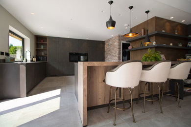 Photo of a large contemporary l-shaped open plan kitchen in Cardiff with an integrated sink, flat-panel cabinets, black cabinets, engineered stone countertops, black appliances, porcelain flooring, an island, grey floors and multicoloured worktops.