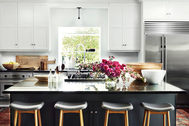 Inspiration for a transitional u-shaped kitchen remodel in Los Angeles with shaker cabinets, white cabinets, white backsplash, subway tile backsplash, stainless steel appliances and an island