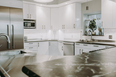 Idéer för ett mellanstort modernt grå kök, med en enkel diskho, släta luckor, vita skåp, bänkskiva i rostfritt stål, beige stänkskydd, stänkskydd i keramik, rostfria vitvaror, en halv köksö, mellanmörkt trägolv och grått golv
