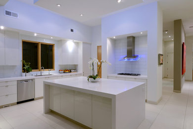 Example of a mid-sized minimalist l-shaped ceramic tile and white floor open concept kitchen design in San Diego with white cabinets, white backsplash, stainless steel appliances, an island, a double-bowl sink, flat-panel cabinets and quartzite countertops