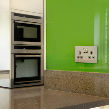 High gloss white contemporary kitchen with green splash back