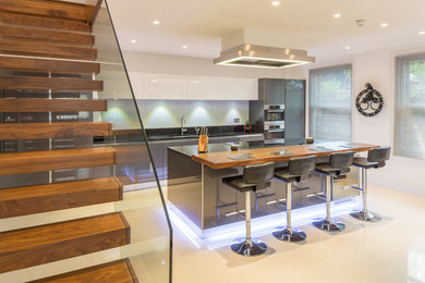 This is an example of a large contemporary open plan kitchen in London with a built-in sink, flat-panel cabinets, grey cabinets, marble worktops, integrated appliances and an island.