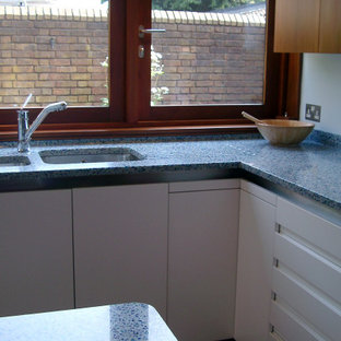 Photo of a mid-sized modern l-shaped kitchen in London with recycled glass benchtops, blue splashback, with island and blue benchtop.
