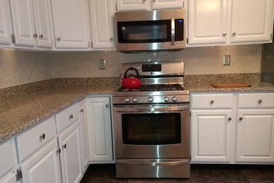 Example of a mid-sized l-shaped kitchen design in Baltimore with an undermount sink, raised-panel cabinets, white cabinets, beige backsplash, subway tile backsplash and stainless steel appliances