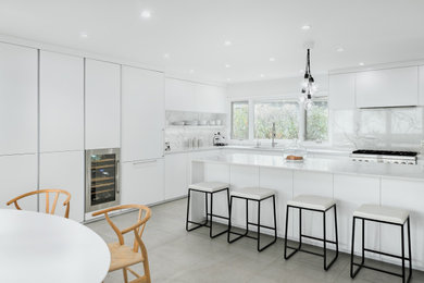 Inspiration for a large contemporary kitchen in Chicago with an integrated sink, recessed-panel cabinets, white cabinets, quartz worktops, white splashback, marble splashback, stainless steel appliances, an island, white worktops and grey floors.