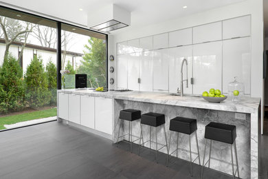 Esempio di un cucina con isola centrale minimal con ante bianche, top in quarzite e pavimento in gres porcellanato
