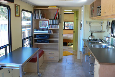 Example of a small eclectic single-wall ceramic tile eat-in kitchen design in San Francisco with a drop-in sink, flat-panel cabinets, light wood cabinets, white appliances and no island