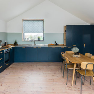 Inspiration for a medium sized scandi l-shaped kitchen/diner in London with a double-bowl sink, flat-panel cabinets, blue cabinets, light hardwood flooring, no island, beige floors, wood worktops, blue splashback and beige worktops.