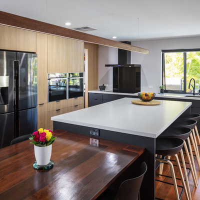 Example of a trendy l-shaped dark wood floor and brown floor eat-in kitchen design in Perth with flat-panel cabinets, gray cabinets, quartz countertops, black backsplash, glass sheet backsplash, gray countertops, an undermount sink, black appliances and an island