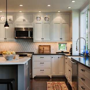 Coastal eat-in kitchen inspiration - Inspiration for a coastal l-shaped eat-in kitchen remodel in Portland Maine with a farmhouse sink, beaded inset cabinets, white cabinets, white backsplash, stone tile backsplash, stainless steel appliances and granite countertops