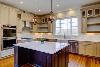 Example of a large farmhouse u-shaped medium tone wood floor open concept kitchen design in Raleigh with a farmhouse sink, shaker cabinets, beige cabinets, quartz countertops, marble backsplash and an island
