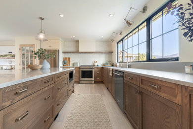 Large cottage l-shaped light wood floor and brown floor eat-in kitchen photo in Vancouver with recessed-panel cabinets, medium tone wood cabinets, quartz countertops, white backsplash, subway tile backsplash, stainless steel appliances, an island and white countertops