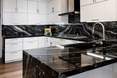 Eat-in kitchen - contemporary u-shaped porcelain tile and black floor eat-in kitchen idea in Los Angeles with an undermount sink, flat-panel cabinets, white cabinets, marble countertops, black backsplash, marble backsplash, stainless steel appliances and black countertops