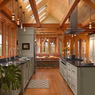 Inspiration for a country galley eat-in kitchen in Burlington with an undermount sink, recessed-panel cabinets, green cabinets, stainless steel appliances, medium hardwood floors, with island and black benchtop.