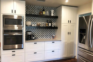 Inspiration for a mid-sized cottage u-shaped medium tone wood floor eat-in kitchen remodel in Austin with an undermount sink, shaker cabinets, yellow cabinets, quartzite countertops, white backsplash, subway tile backsplash, stainless steel appliances, a peninsula and gray countertops