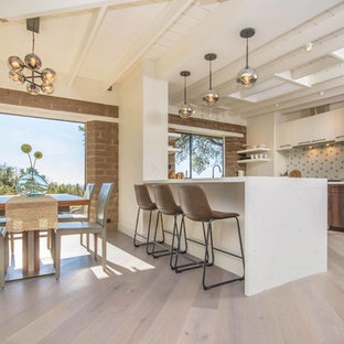 Idee per una cucina minimalista con ante lisce, ante in legno scuro, paraspruzzi bianco, elettrodomestici in acciaio inossidabile, parquet chiaro, penisola, pavimento beige e top bianco