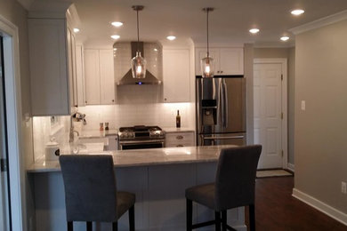 Kitchen - mid-sized transitional l-shaped dark wood floor kitchen idea in Baltimore with shaker cabinets, white cabinets, white backsplash, subway tile backsplash, stainless steel appliances and a peninsula