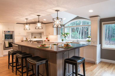 Inspiration for a huge transitional medium tone wood floor eat-in kitchen remodel in Boston with a double-bowl sink, recessed-panel cabinets, white cabinets, granite countertops, white backsplash, subway tile backsplash, stainless steel appliances and two islands