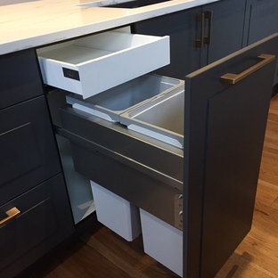 Inspiration for a mid-sized midcentury l-shaped eat-in kitchen in Edmonton with an undermount sink, shaker cabinets, grey cabinets, quartz benchtops, white splashback, subway tile splashback, stainless steel appliances, light hardwood floors, with island and white benchtop.