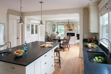 Example of a large transitional l-shaped light wood floor open concept kitchen design in Boston with an undermount sink, flat-panel cabinets, white cabinets, granite countertops, black backsplash, stone slab backsplash, stainless steel appliances and an island