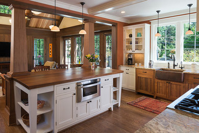 Bild på ett mellanstort lantligt kök, med en rustik diskho, skåp i shakerstil, vita skåp, granitbänkskiva, beige stänkskydd, stänkskydd i tunnelbanekakel, rostfria vitvaror, mörkt trägolv och en köksö