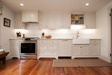 Example of a mid-sized classic galley medium tone wood floor and brown floor enclosed kitchen design in Philadelphia with a farmhouse sink, beaded inset cabinets, beige cabinets, marble countertops, white backsplash, ceramic backsplash, stainless steel appliances and no island