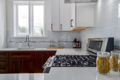 Mid-sized transitional u-shaped eat-in kitchen photo in Vancouver with recessed-panel cabinets, a peninsula, an undermount sink, dark wood cabinets, quartzite countertops, white backsplash, glass tile backsplash and stainless steel appliances