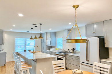 Mid-sized trendy u-shaped light wood floor and brown floor eat-in kitchen photo in Raleigh with an undermount sink, shaker cabinets, gray cabinets, quartzite countertops, white backsplash, porcelain backsplash, white appliances, an island and white countertops