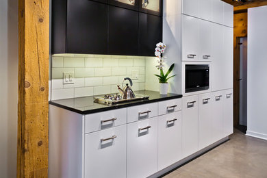 Inspiration for a large modern galley concrete floor and gray floor open concept kitchen remodel in Minneapolis with an undermount sink, flat-panel cabinets, black cabinets, quartzite countertops, white backsplash, porcelain backsplash, stainless steel appliances, an island and black countertops