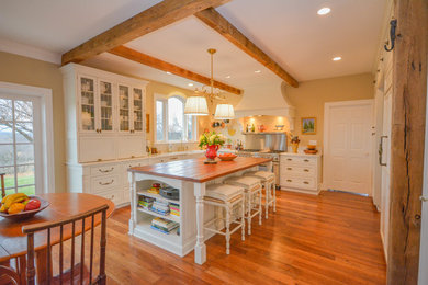 Example of a large cottage u-shaped medium tone wood floor and brown floor eat-in kitchen design in DC Metro with a farmhouse sink, shaker cabinets, white cabinets, quartz countertops, white backsplash, porcelain backsplash, paneled appliances and an island